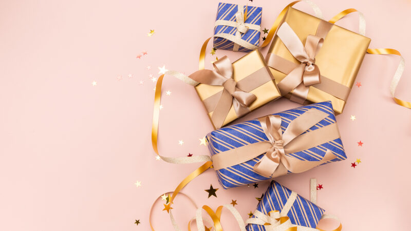 Festive christmas new year background colorful and gold gift boxes and holiday decorations on pink background. New Year's present and Christmas present top view